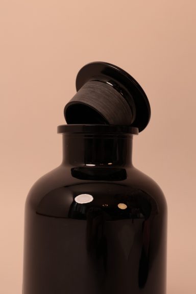 Schwarze Flasche mit abnehmbarem Verschluss auf hellem Hintergrund.